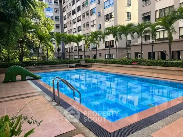 Luxurious residential pool area with lush greenery and modern building backdrop.