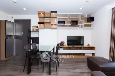 Modern living room with stylish shelving and dining area, featuring sleek furniture and contemporary decor.