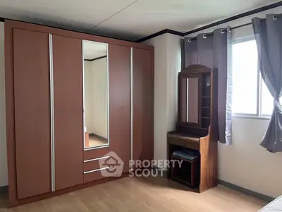 Spacious bedroom with large wardrobe and natural light through window.