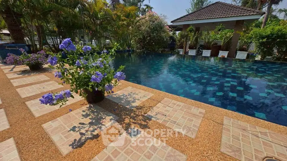 Luxurious outdoor pool area with lush greenery and elegant tile design, perfect for relaxation and entertainment.