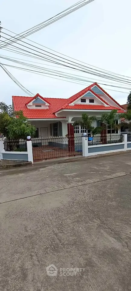 Charming single-story house with red roof and lush greenery, perfect for family living.