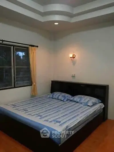 Cozy bedroom with large bed and window view, perfect for relaxation.