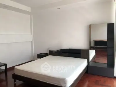 Spacious bedroom with modern furniture and hardwood floors in a minimalist design.