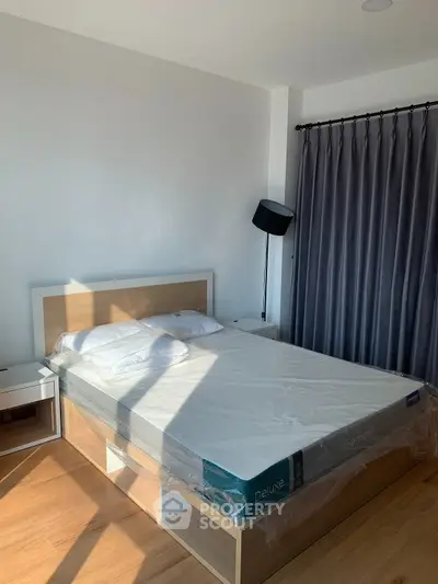 Modern bedroom with natural light, featuring a stylish bed and elegant curtains.