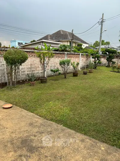 Spacious garden area with lush greenery and potted plants, perfect for outdoor relaxation and activities.