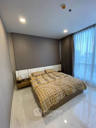 Modern bedroom with large window and stylish decor in a high-rise apartment.