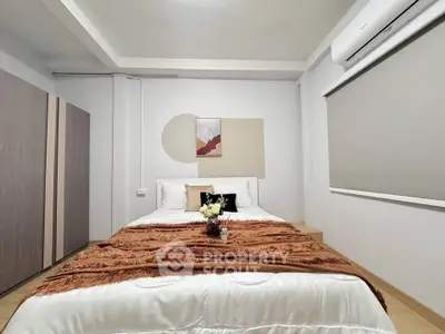 Modern bedroom with stylish decor and air conditioning, featuring a cozy bed and elegant furnishings.