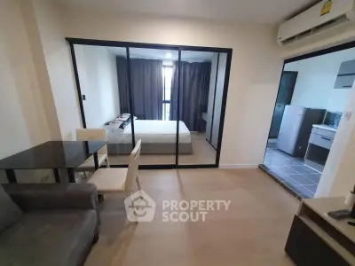 Modern apartment interior with glass-walled bedroom and open living area, featuring sleek furniture and air conditioning.