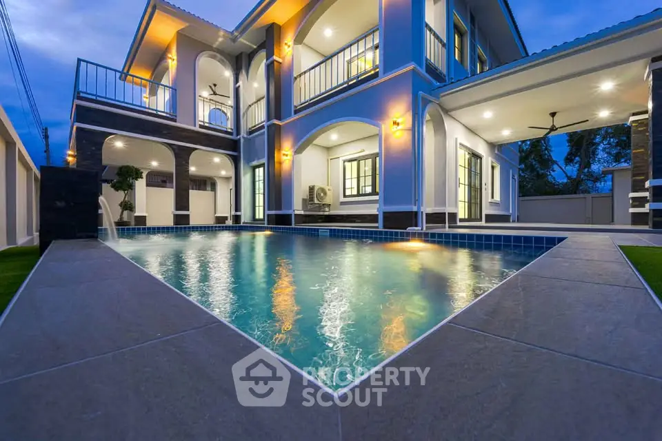 Luxurious modern home with stunning pool and elegant lighting at dusk.