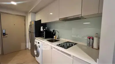 Modern kitchen with sleek appliances and washing machine in compact layout.