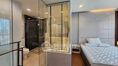 Luxurious bedroom with ensuite bathroom featuring glass partition and modern design.