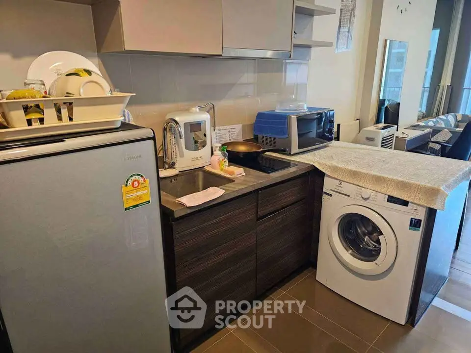 Modern kitchen with appliances including fridge, washing machine, and microwave in a compact layout.