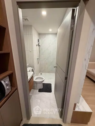 Modern bathroom with sleek design and tiled walls, featuring a toilet and shower area.