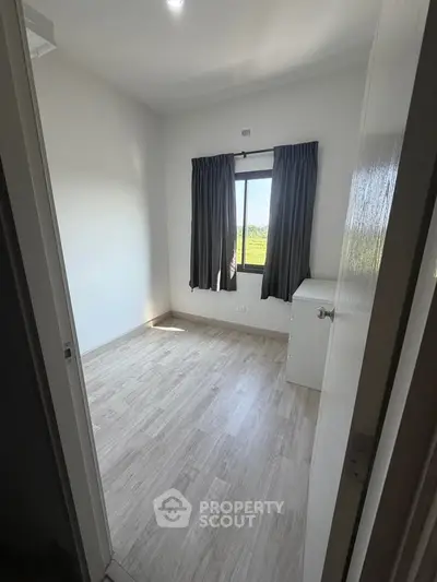 Bright empty bedroom with wooden flooring and large window view