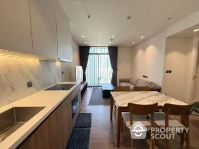 Modern open-plan living room with kitchen and dining area, featuring sleek design and natural light.