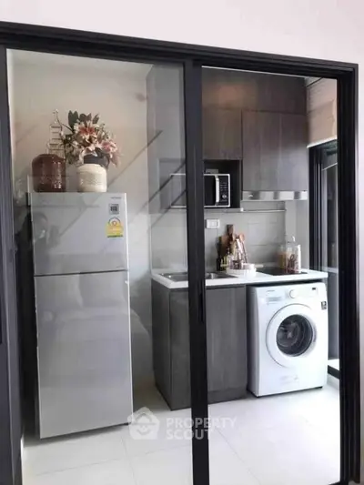 Modern compact kitchen with sleek appliances and stylish cabinetry in a cozy apartment setting.