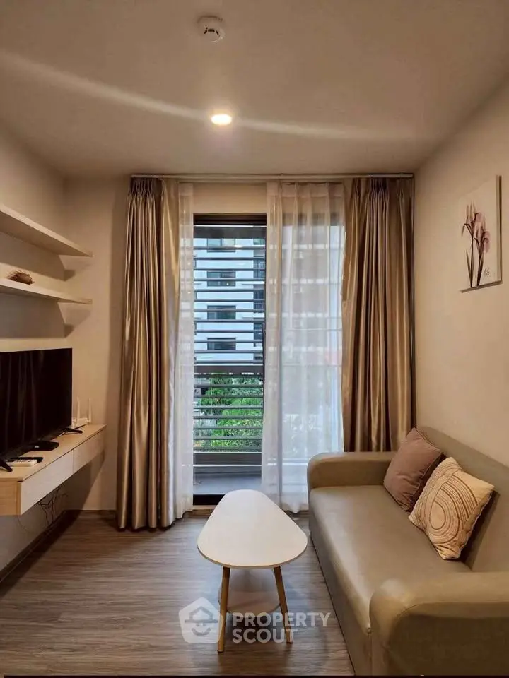 Modern living room with sleek furniture and large window offering city view.