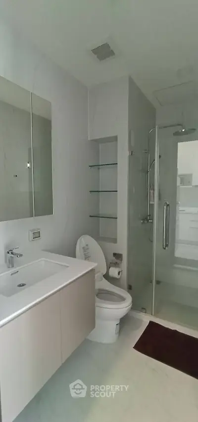 Modern bathroom with sleek design, featuring a glass shower and elegant fixtures.