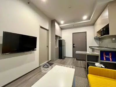 Modern living room with sleek kitchen, flat-screen TV, and stylish furniture in a contemporary apartment.