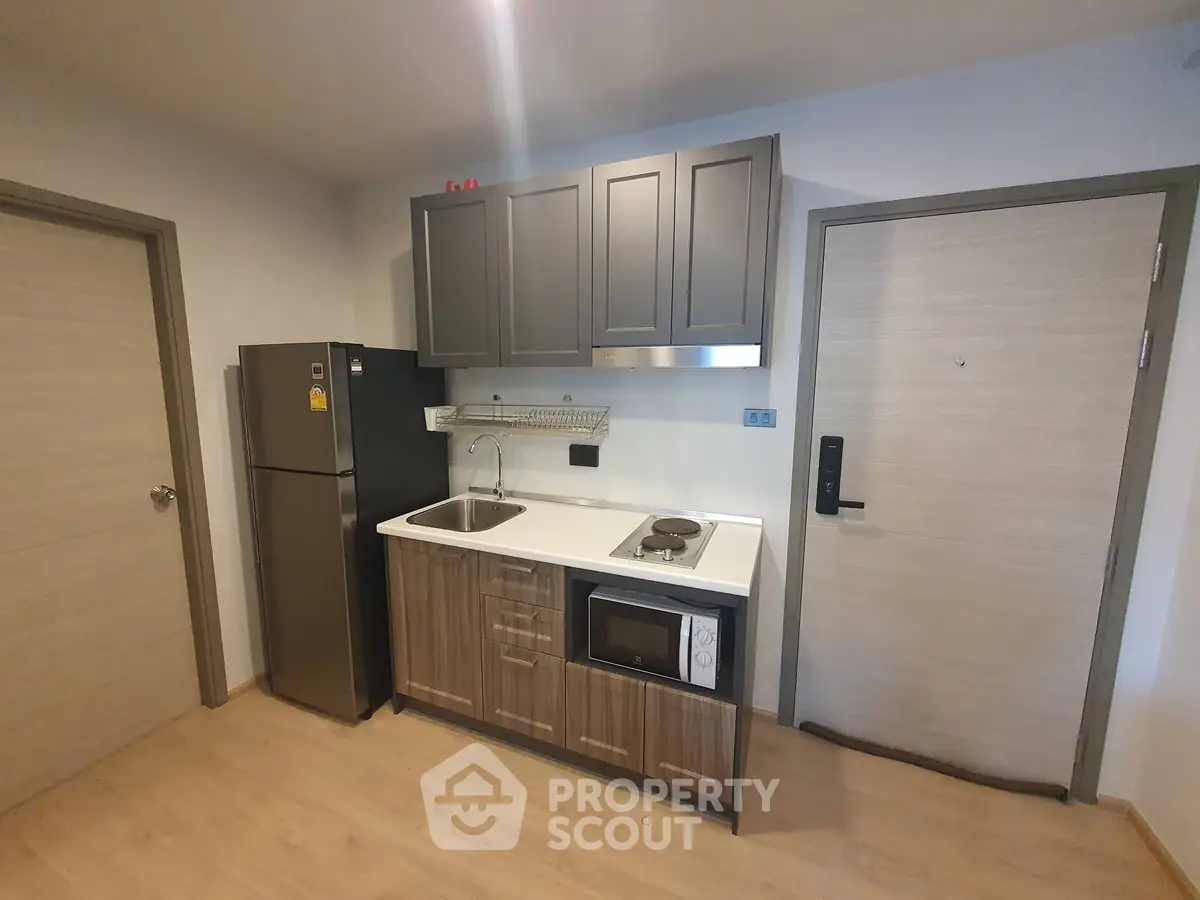 Modern compact kitchen with sleek cabinetry and appliances in a stylish apartment.