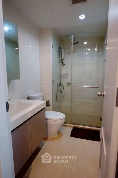 Modern bathroom with glass shower and sleek vanity in contemporary apartment.