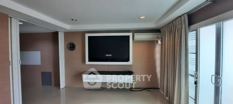 Spacious living room with modern TV setup and sliding glass doors