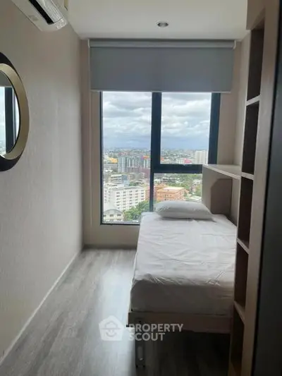 Modern bedroom with city view, featuring a single bed and large window for natural light.