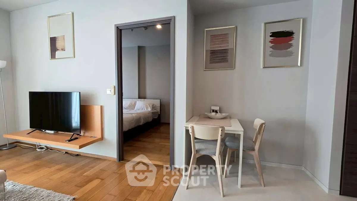 Modern apartment interior with TV, dining area, and bedroom view