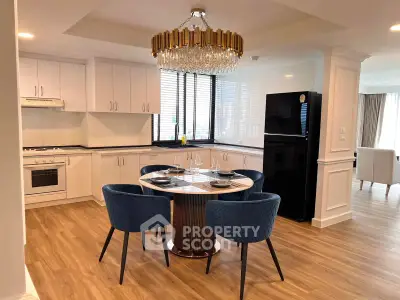 Elegant kitchen with open layout, featuring modern appliances and stylish dining area with chandelier.