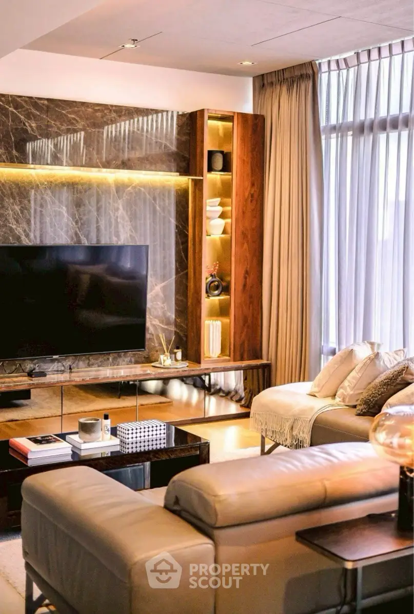 Luxurious living room with modern decor, large TV, and elegant lighting