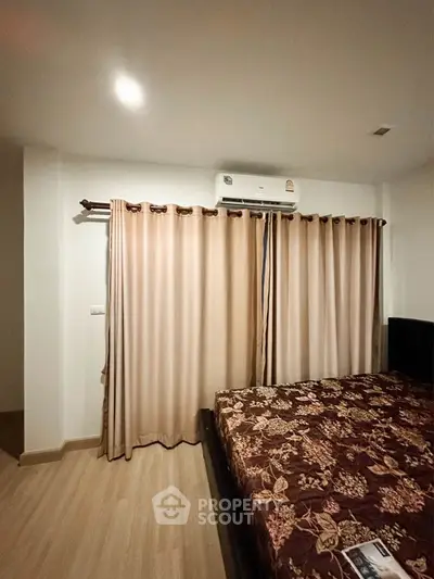 Cozy bedroom with floral bedspread and air conditioning, perfect for relaxation.