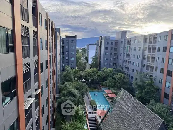 Stunning view of modern apartment complex with lush greenery and inviting pool area.