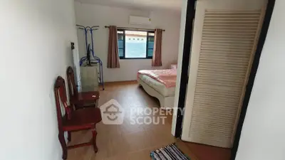 Cozy bedroom with natural light, featuring a bed, chairs, and air conditioning, ideal for comfort and relaxation.