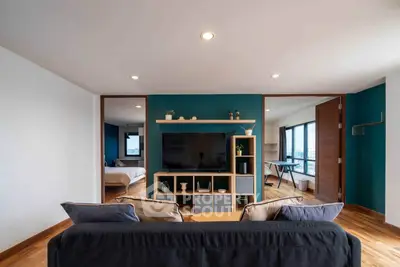 Modern living room with open layout and stylish decor, featuring a cozy seating area and a view into the bedroom.