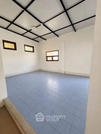 Spacious room with blue tiled floor and modern ceiling design, ideal for versatile use.
