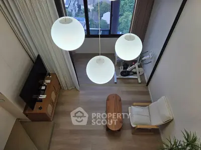 Modern living room with large windows and exercise bike, featuring stylish lighting and wooden furniture.