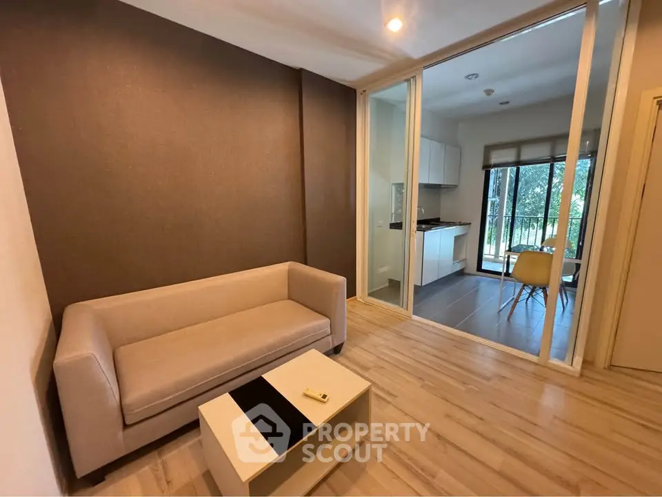 Modern living room with open layout to kitchen and balcony view.