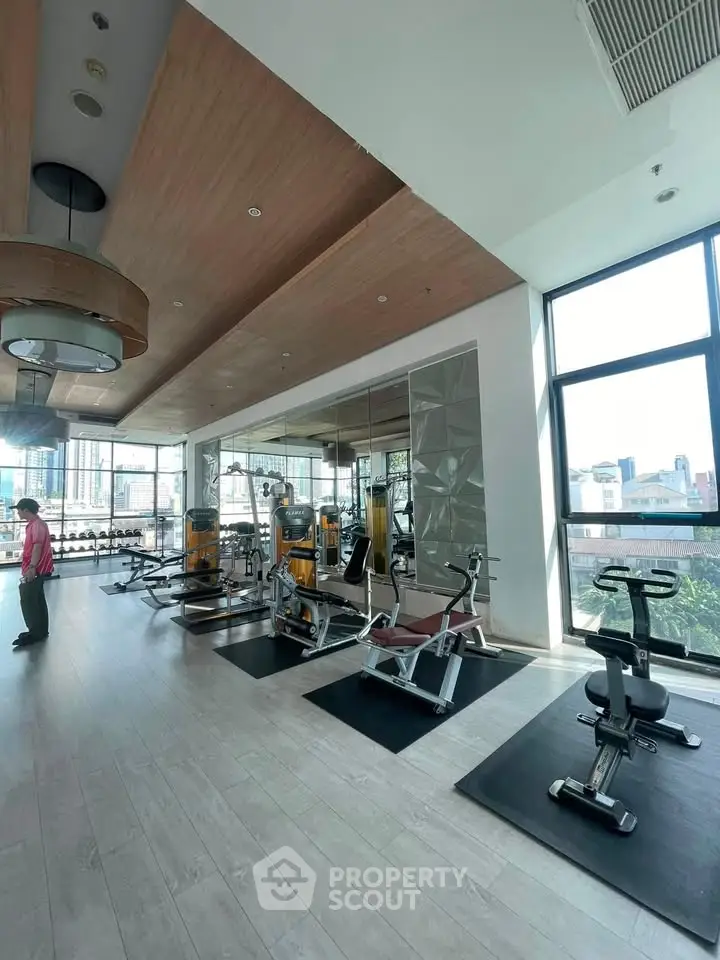 Spacious modern gym with large windows and fitness equipment in a luxury residential building.