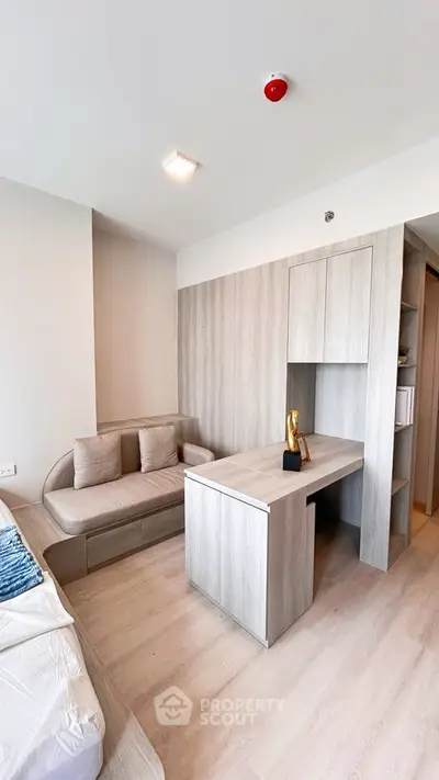 Modern study room with sleek wooden desk and cozy seating area in a stylish apartment.
