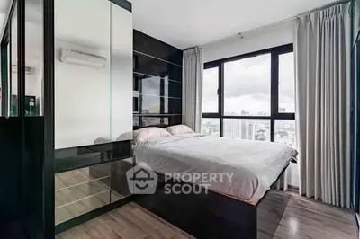 Modern bedroom with large windows and city view, featuring sleek black furniture and elegant decor.