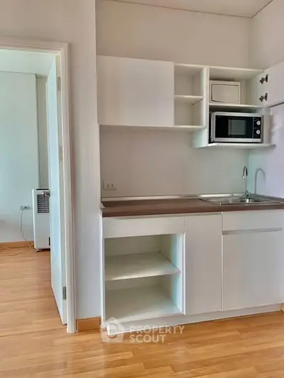 Modern compact kitchen with sleek cabinetry and built-in microwave in a cozy apartment.
