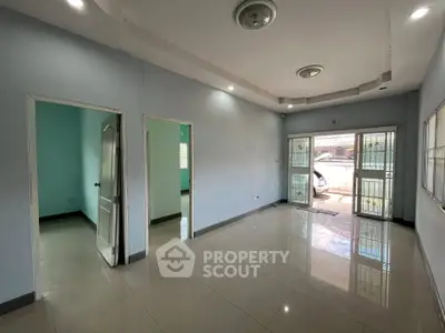 Spacious living room with tiled flooring and ample natural light, featuring modern ceiling lights and access to outdoor area.
