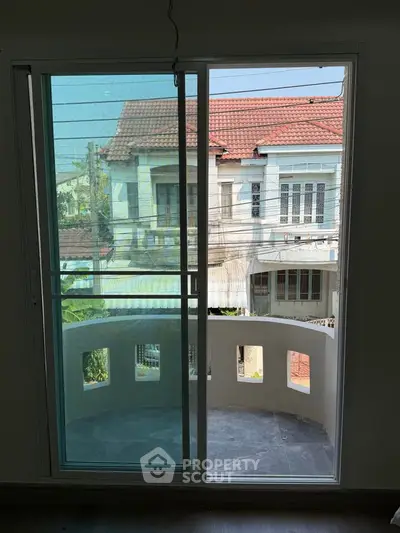 Spacious balcony with sliding glass door offering a view of charming neighborhood houses.