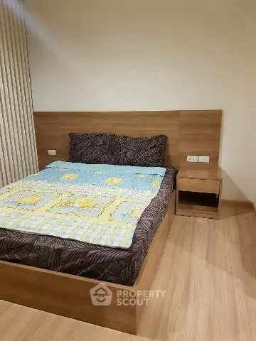 Cozy bedroom with wooden flooring and modern bed frame, perfect for relaxation.