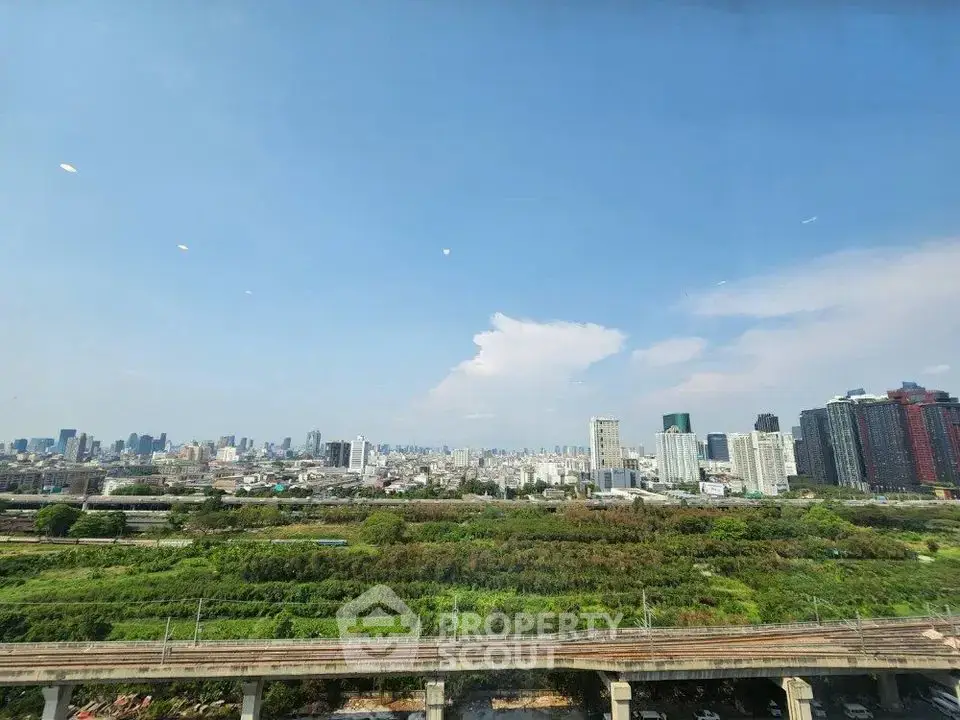 Stunning cityscape view with lush greenery and urban skyline under clear blue sky.