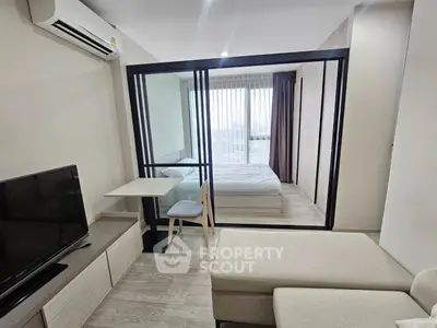 Modern studio apartment with glass partition, cozy living area, and natural light-filled bedroom.