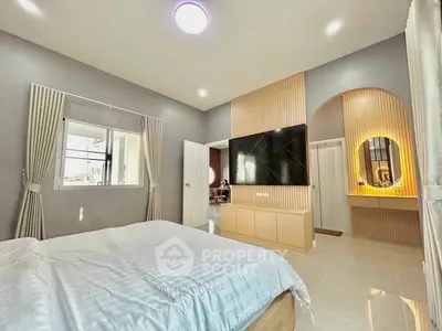 Spacious modern bedroom with stylish decor and large TV, perfect for relaxation.