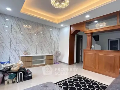 Spacious living room with elegant marble wall and modern chandelier lighting.