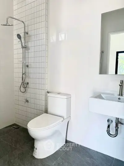 Modern bathroom with sleek fixtures and minimalist design, featuring a shower and toilet.