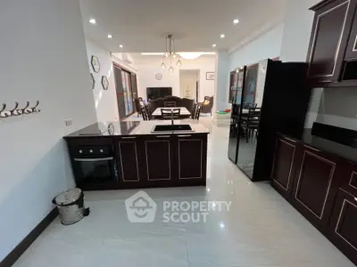 Spacious modern kitchen with sleek cabinetry and open layout, leading to a stylish dining area.